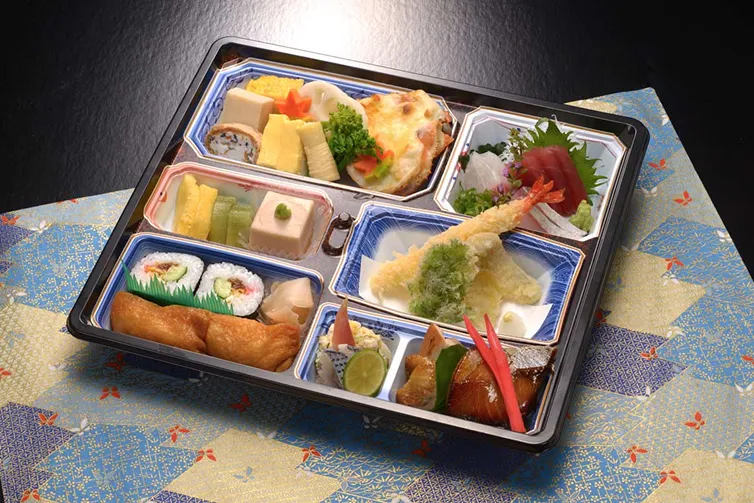 和食仕出し弁当。エビ天ぷら、刺身、焼き魚、煮物、寿司、出汁巻き卵など、季節の味覚を詰め込んだ一品。