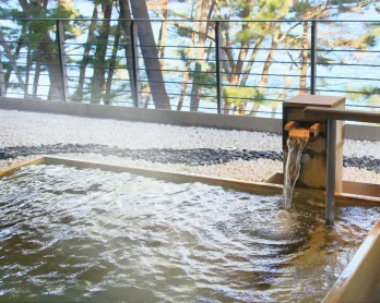 滑らかな石畳に囲まれた木の温もりを感じる丸型露天風呂。