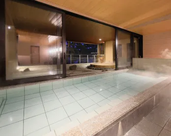 手前に正方形のタイル張りの内湯があり、湯気が立っている。奥はガラス戸で仕切られたバルコニーで、木製の露天風呂があります。