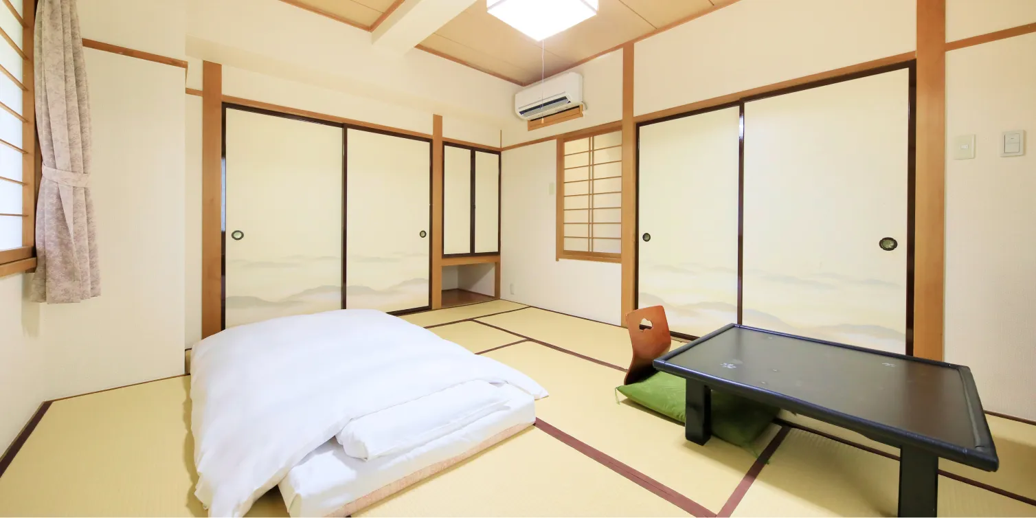 木製の格子窓と障子戸のある、広々とした畳敷きの和室。