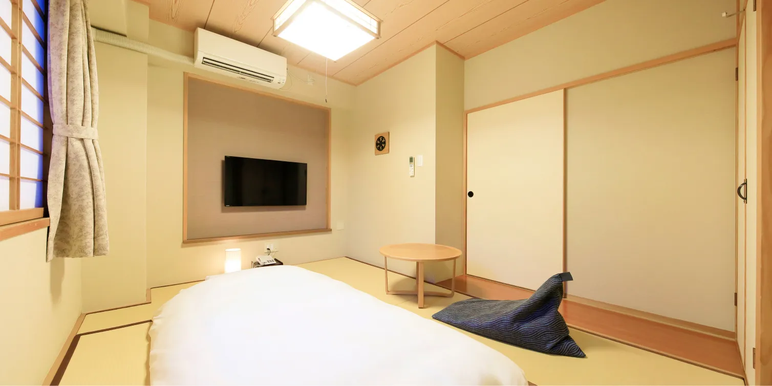 壁にはテレビが掛けられ、天井には照明器具があり、エアコンも設置されています。